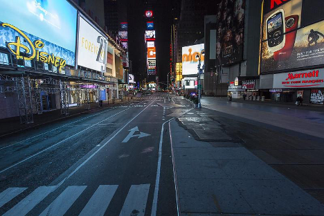 The photo is an empty street at night. There are billboards lit up and signs advertising products, but the street is empty of all cars, bikes, and people.