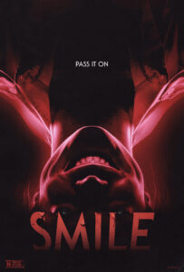 The photo is the promotional poster for the 2022 horror movie Smile. In the poster, a woman is shown upside down, and smiling a wide smile. Her teeth appear as fangs. The tagline of the movie says Pass It On.